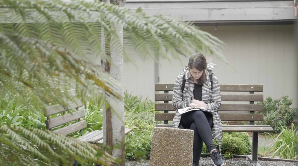 woman in coat on a bench with her Bible praying