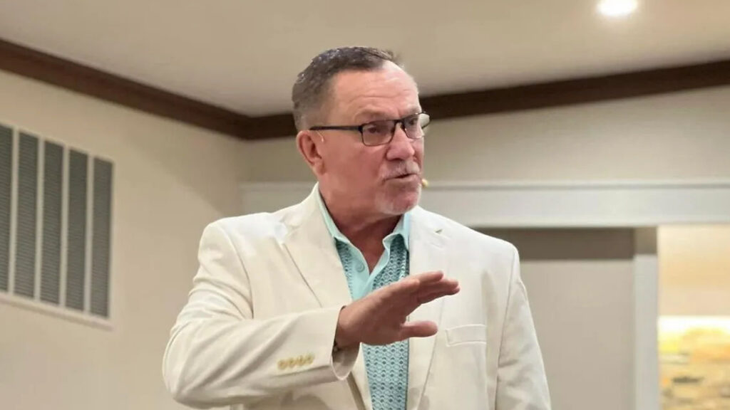 Preacher in a white jacket gesturing with his right hand